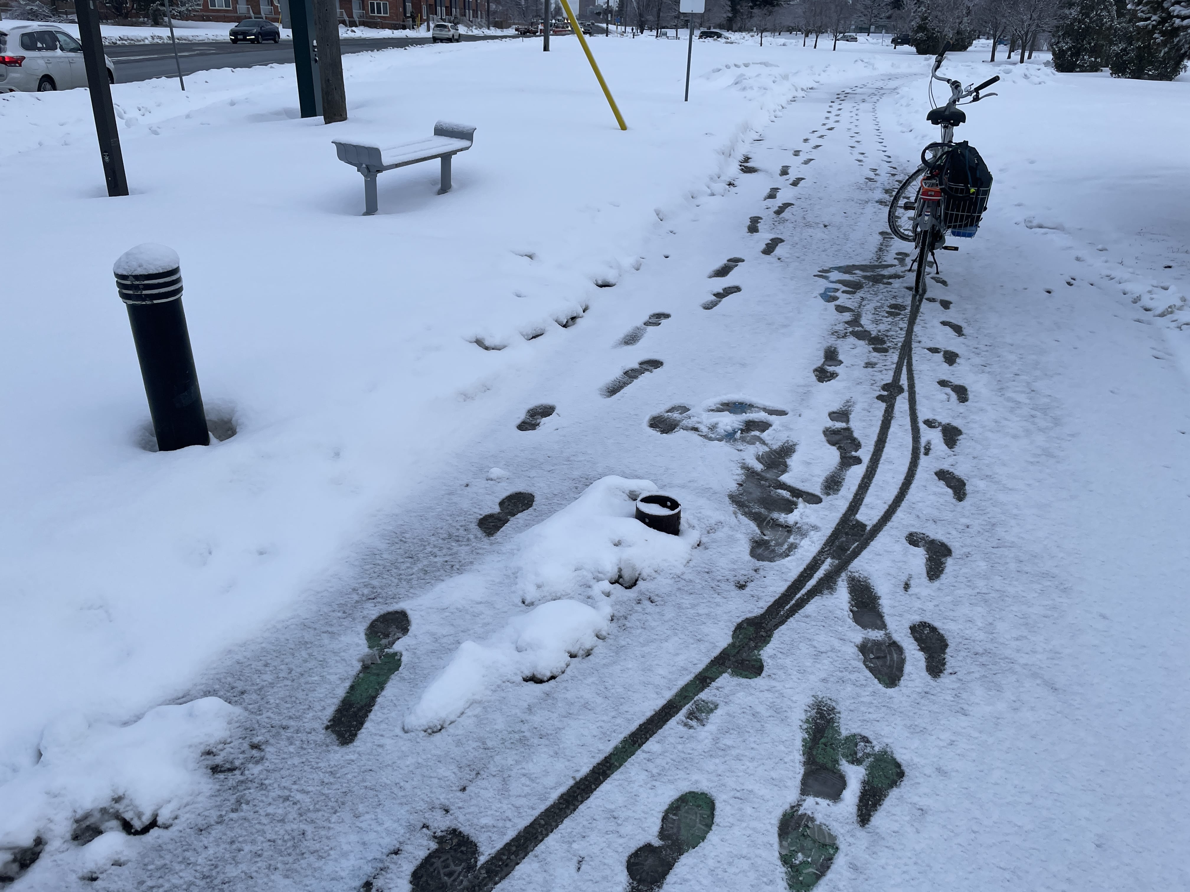 Photo of Thomson Memorial park trail with a bike in the foreground and visible footsteps and tyre marks in the light snow.
